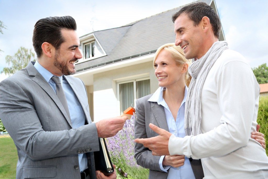 Real estate agent giving keys to couple