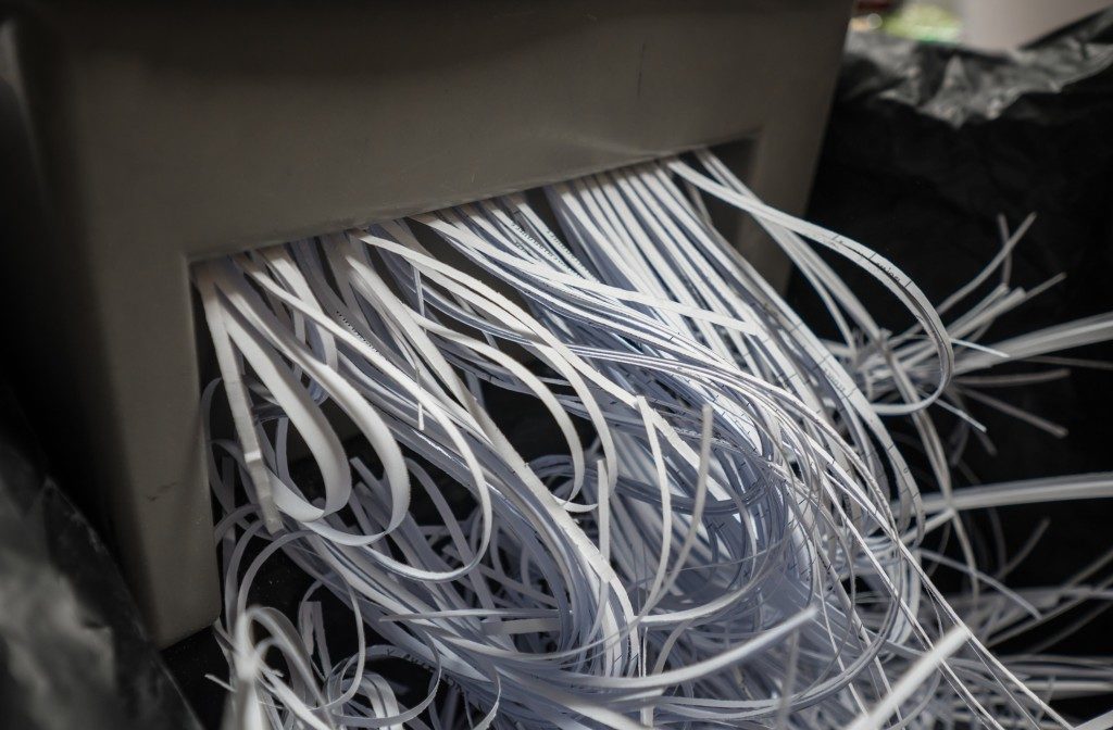 documents being shredded through a shredding machine