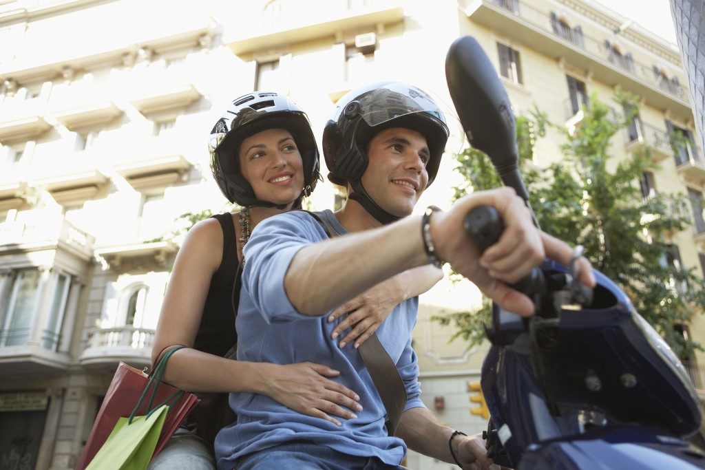 Young couple smiling while enjoying road trip on scooter