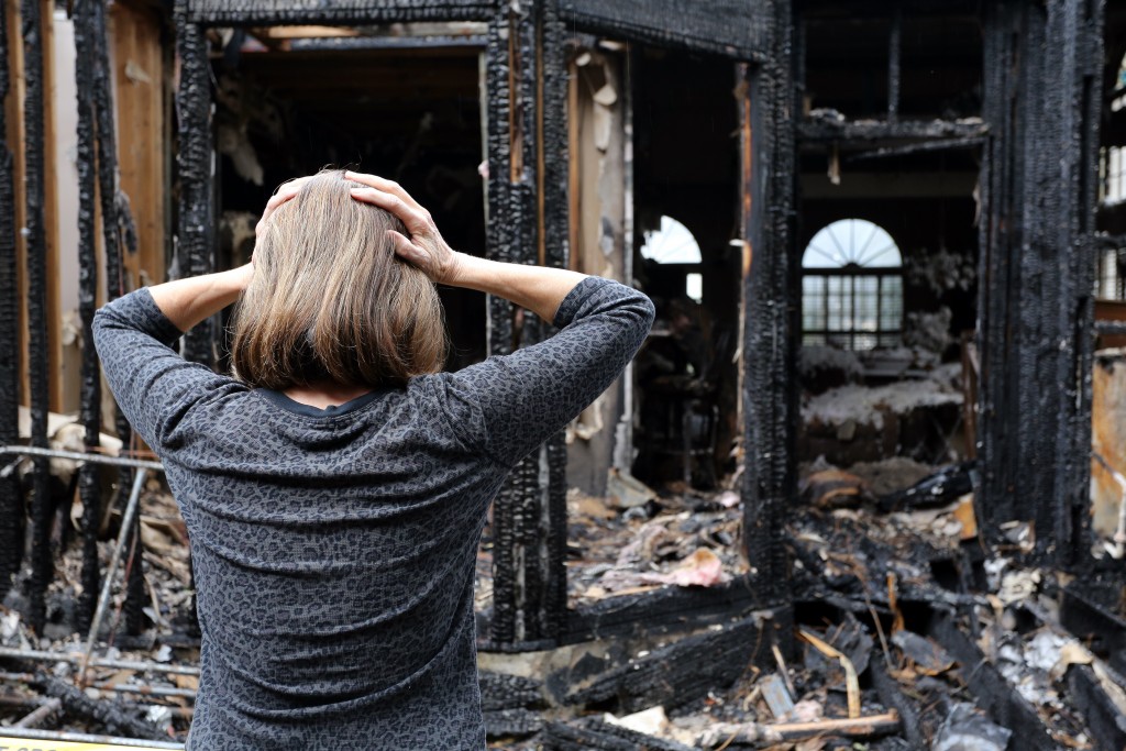 woman looking at a burned down house