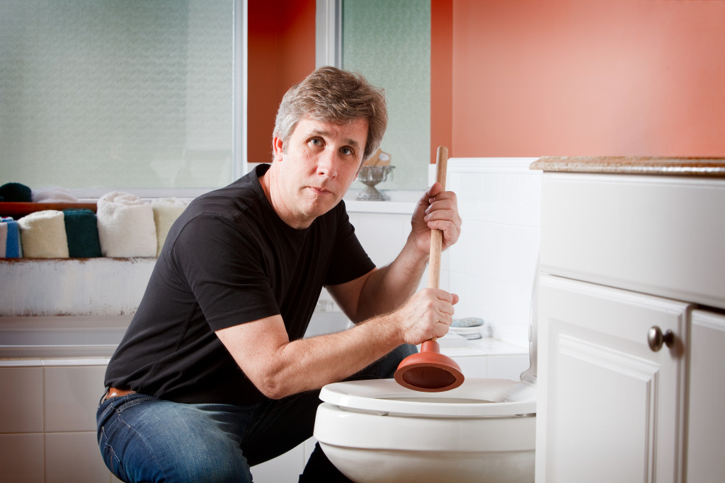 man fixing a clogged toilet