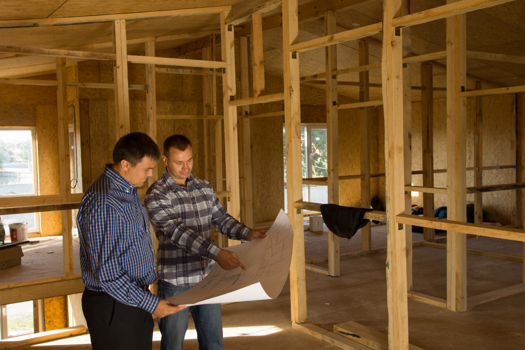 client and business owner looking at a plan of a house that is currently being constructed