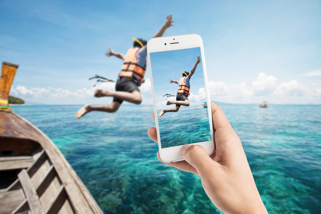taking a photo of a snorkeling diver jump in the water using a smartphone