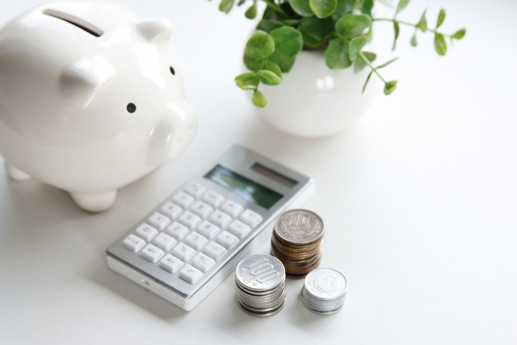 A piggy bank, calculator, coins, and a plant