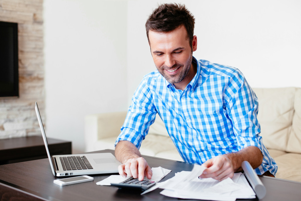 Smiling young man analyzing his expenses and paying online