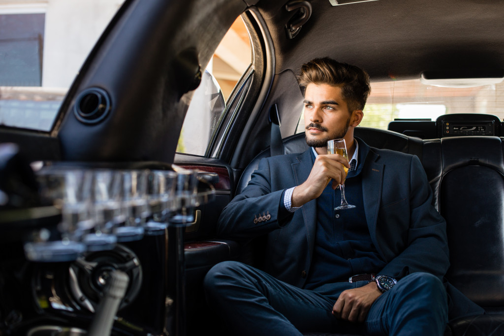 man drinking champagne in a limo