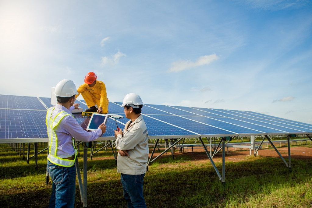 three men in a field setting up solar panels