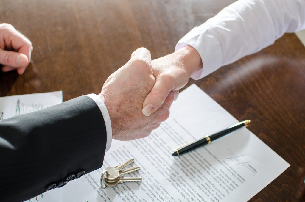 An estate agent shaking hands with client over a contract