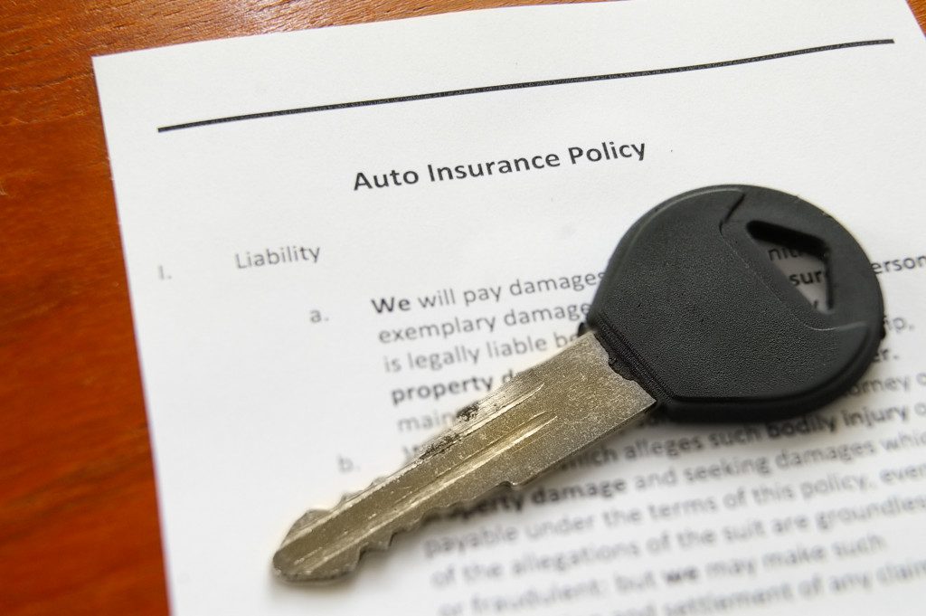 A car key on tops of an auto insurance policy document