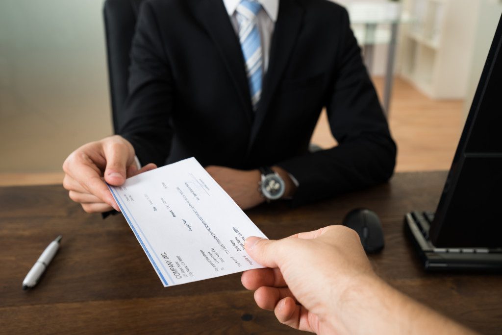 A check held by a business person and a client in an office