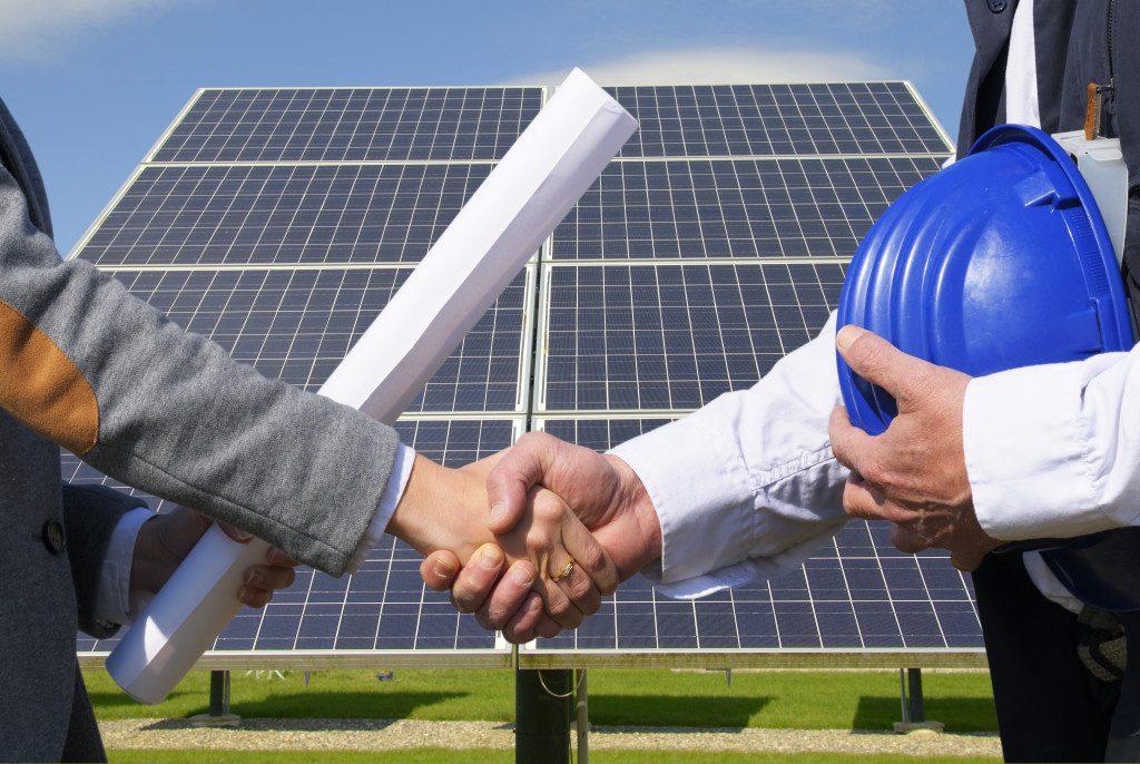 a handshake between businessman and contractor with solar panel in the background