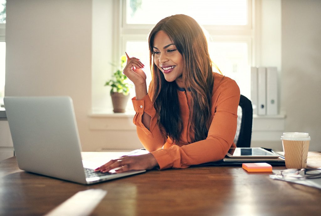 female entrepreneur sitting at a table in her home office working on a laptop