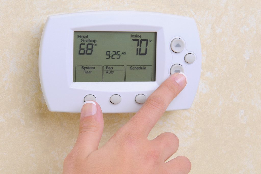 A hand touching the buttons on a thermostat
