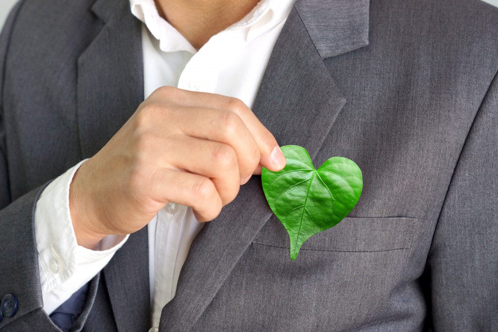 A business person putting a green leaf in their coat's pocket